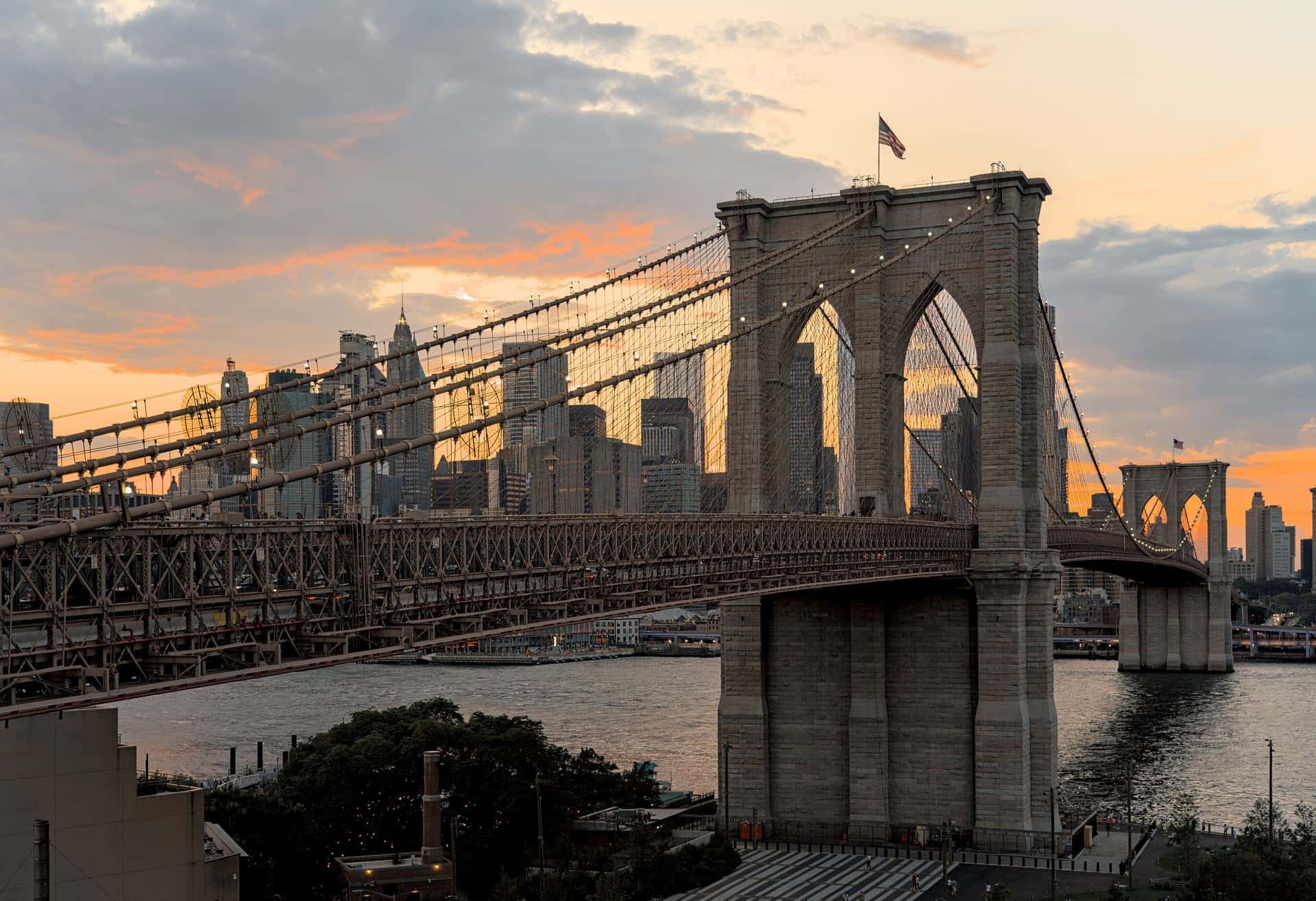 Brooklyn Bridge at sunset seen from a rooftop in DUMBO, with Lower Manhattan behind