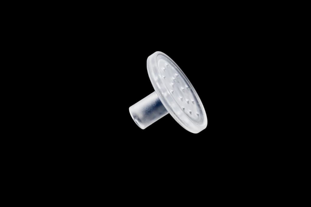 CuraCator applicator head isolated on black background showing the Luer-lock connector and multi-port dispensing disc