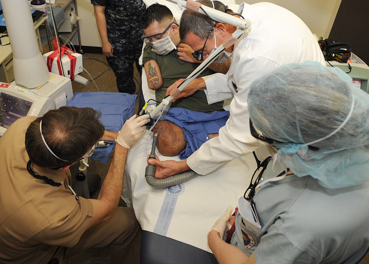 Two dermatologic surgeons in protective eyewear performing fractional carbon dioxide laser resurfacing on a patient