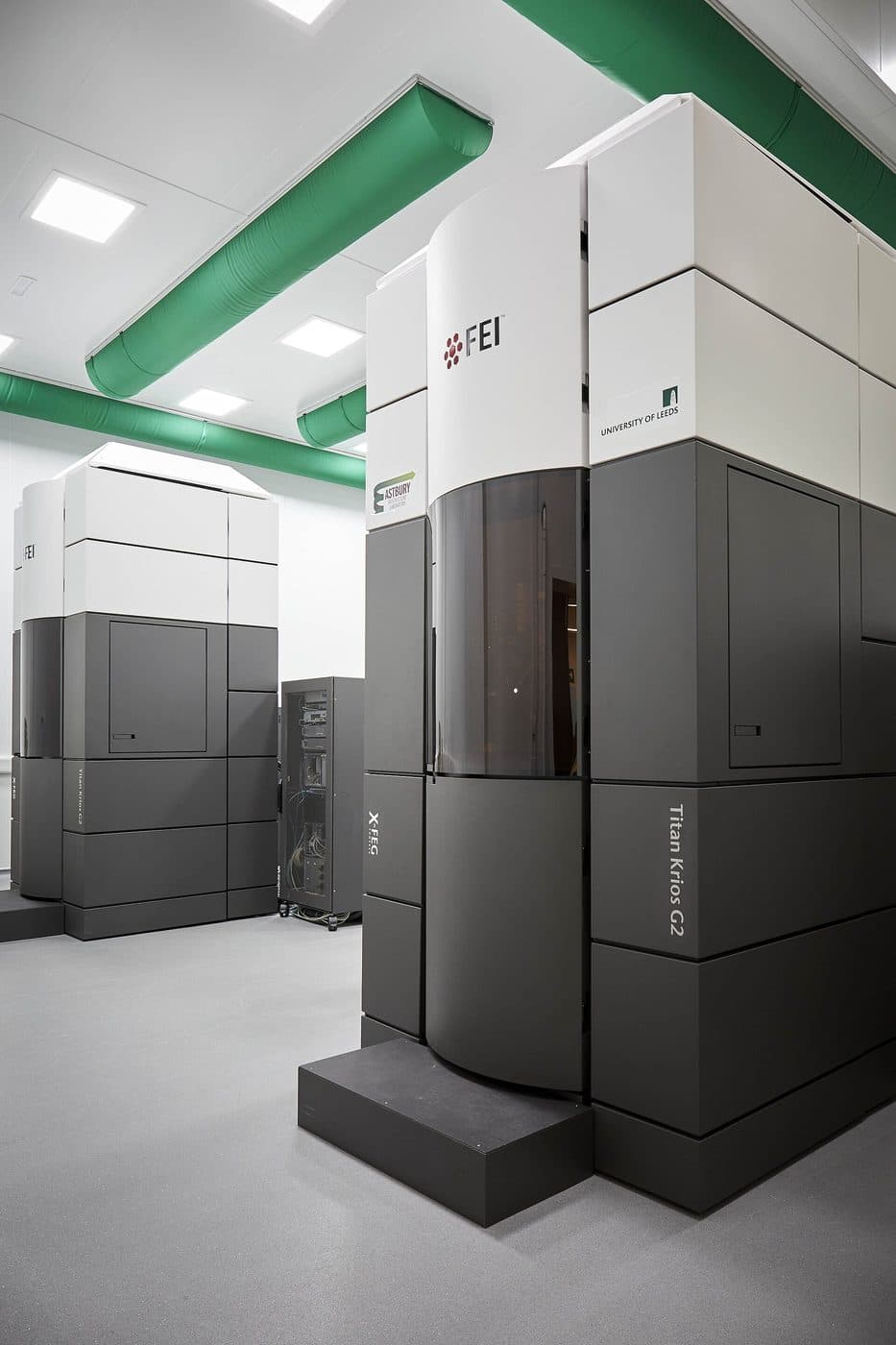Two tall white and grey cryo-electron microscope enclosures standing in a clean instrument room